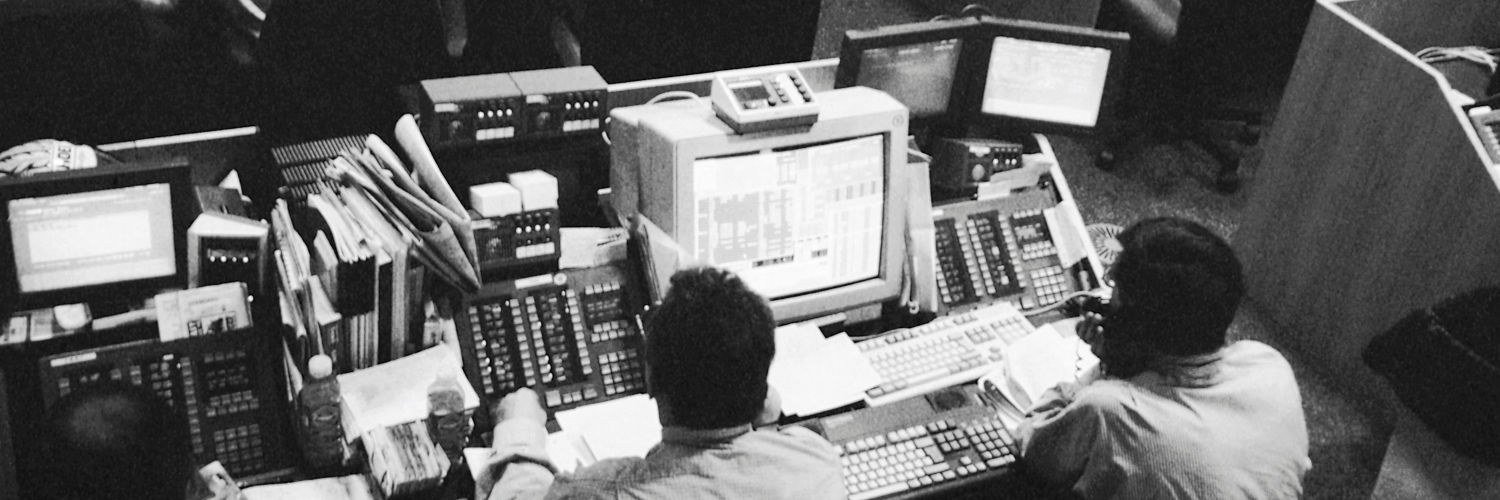 Vintage (black-and-white) photo of stock brokers monitoring computers. Header image for blog, "Stop Blaming the Economy, Maybe it's Us"